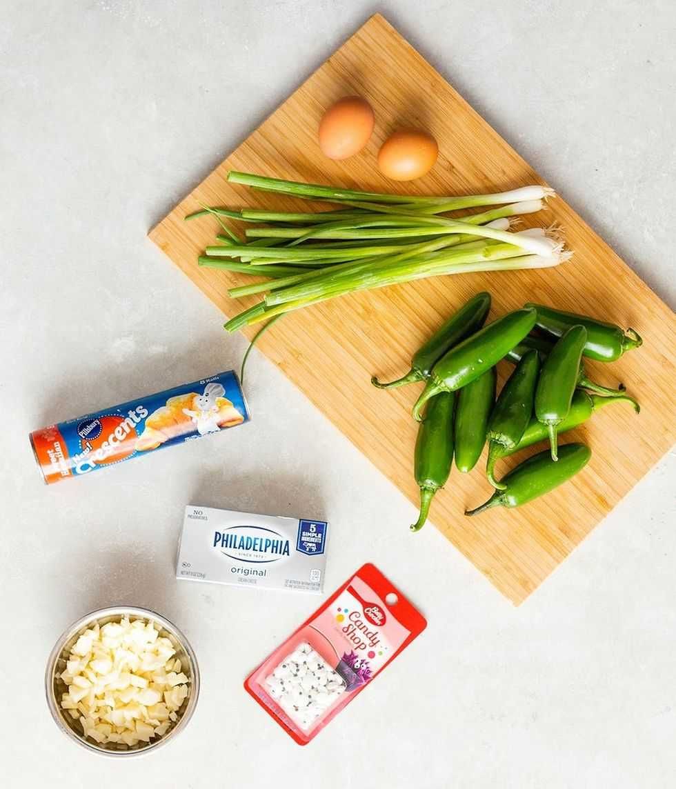 Ingredients on a board: eggs, spring onions, jalape\u00f1os, with cheese and dough nearby.