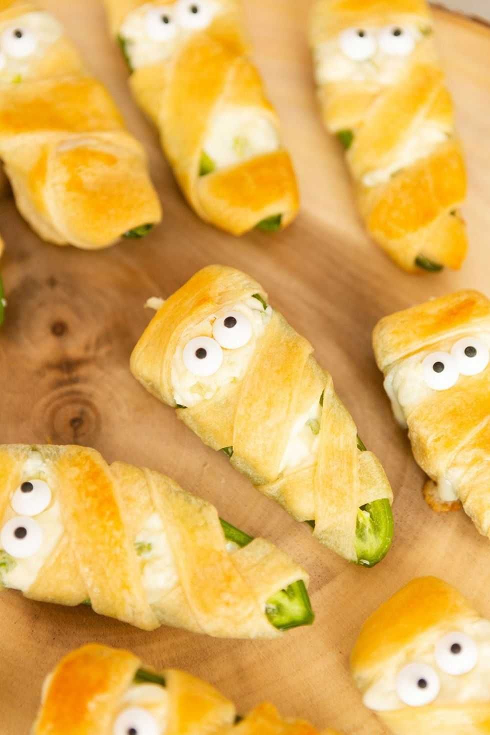 Jalape\u00f1o poppers wrapped in dough, designed to look like mummies with candy eyes.