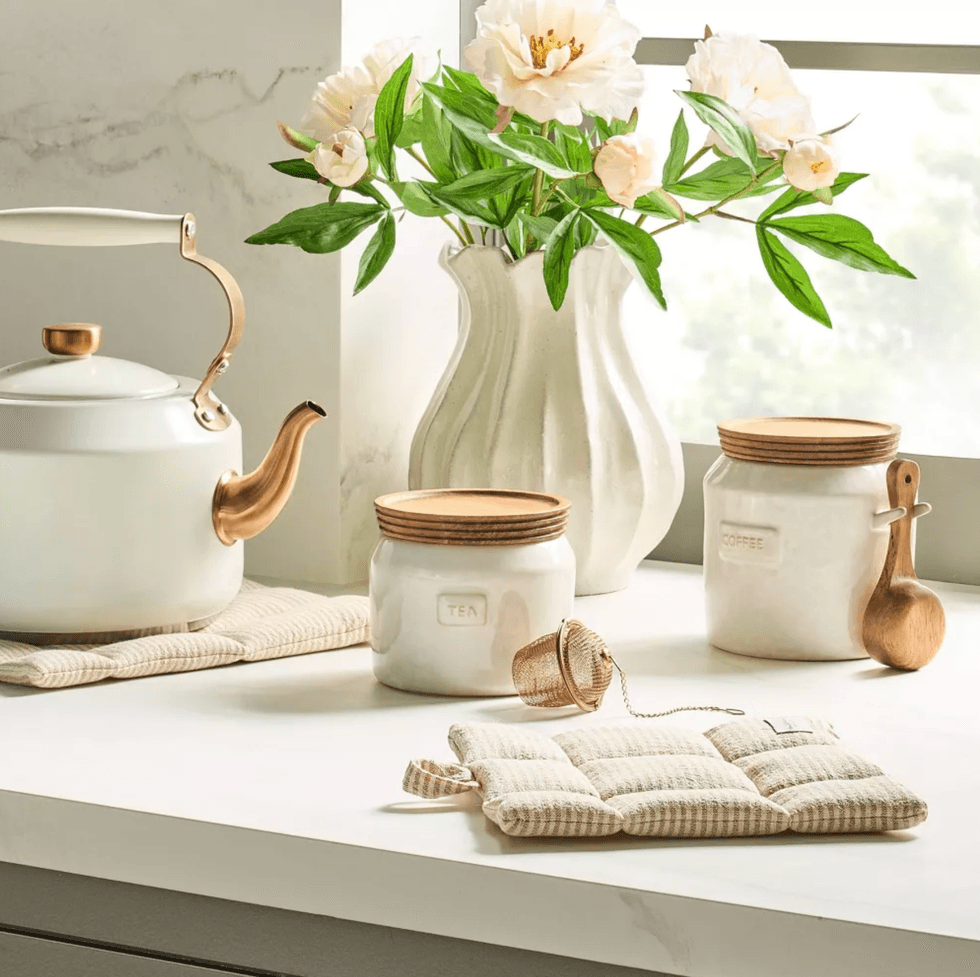 Kitchen counter with a teapot, canisters, flowers, and a tea infuser.