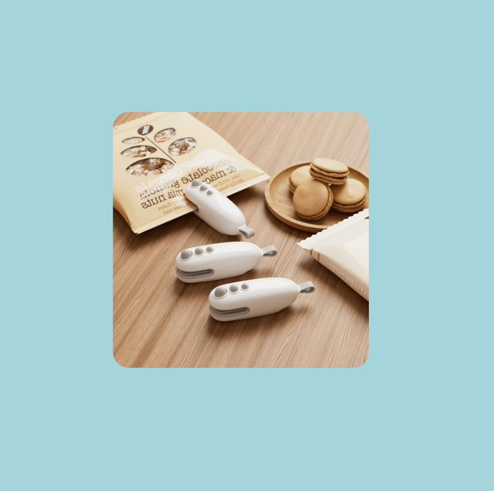 Kitchen gadgets and packaged snacks on a wooden surface with a teal background.