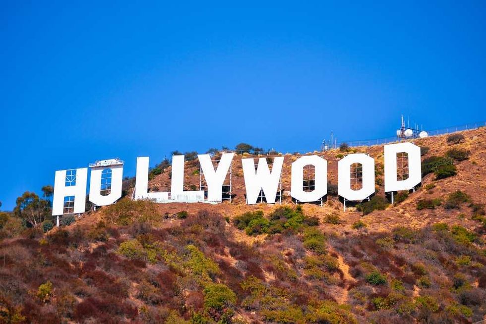 Large white "HOLLYWOOD" sign on a dry, brown hillside under a clear blue sky.