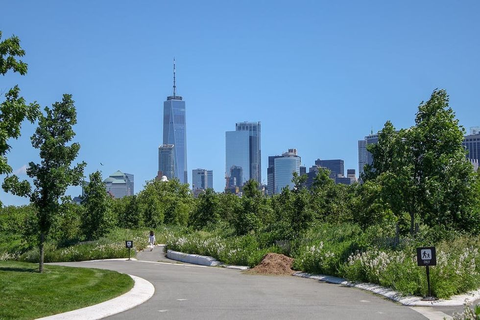 Leafy paths and Manhattan skyline viewed from the park on Governors Island, New York, NY
