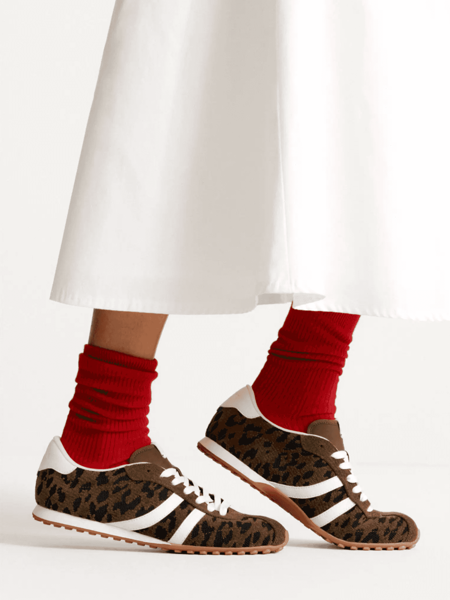Leopard-print sneakers with red socks and white skirt.