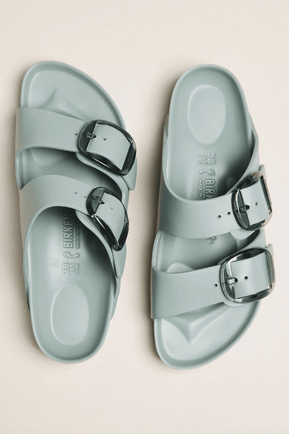 Light green sandals with two black buckles on each foot.