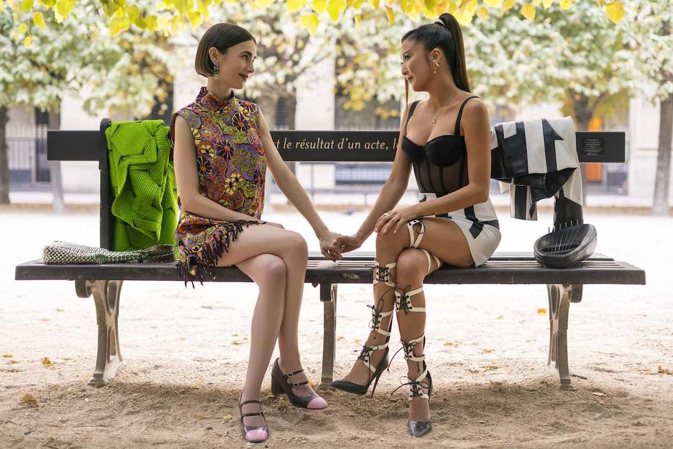 lily collins and ashley park sitting on a bench in paris