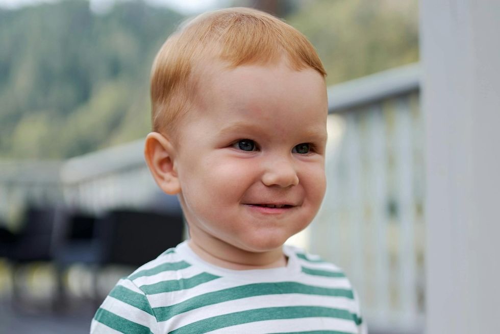 little boy in a striped green tshirt smiling