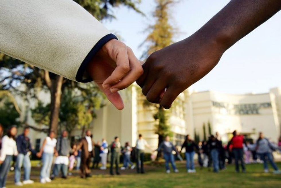 LOS ANGELES, CA - APRIL 21: Students pray in the aftermath of two apparent racially motivated student brawls at Thomas Jefferson High School April 21, 2005 in Los Angeles, California. A number of students suffered injuries this week while fleeing from a lunch period brawl involving about 200 Latino and African-American students, the second racially charged incident in less than a week. Stepped-up school police and Los Angeles police presence, strict regulation of clothing styles that could be associated with gangs, and a tightened school bell schedule that leaves little time to linger between classes are in effect to curb the violence. (Photo by David McNew/Getty Images)