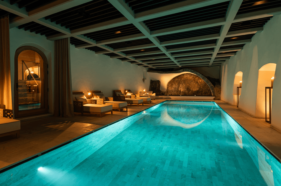 Luxurious indoor pool with ambient lighting and modern seating by the sides.