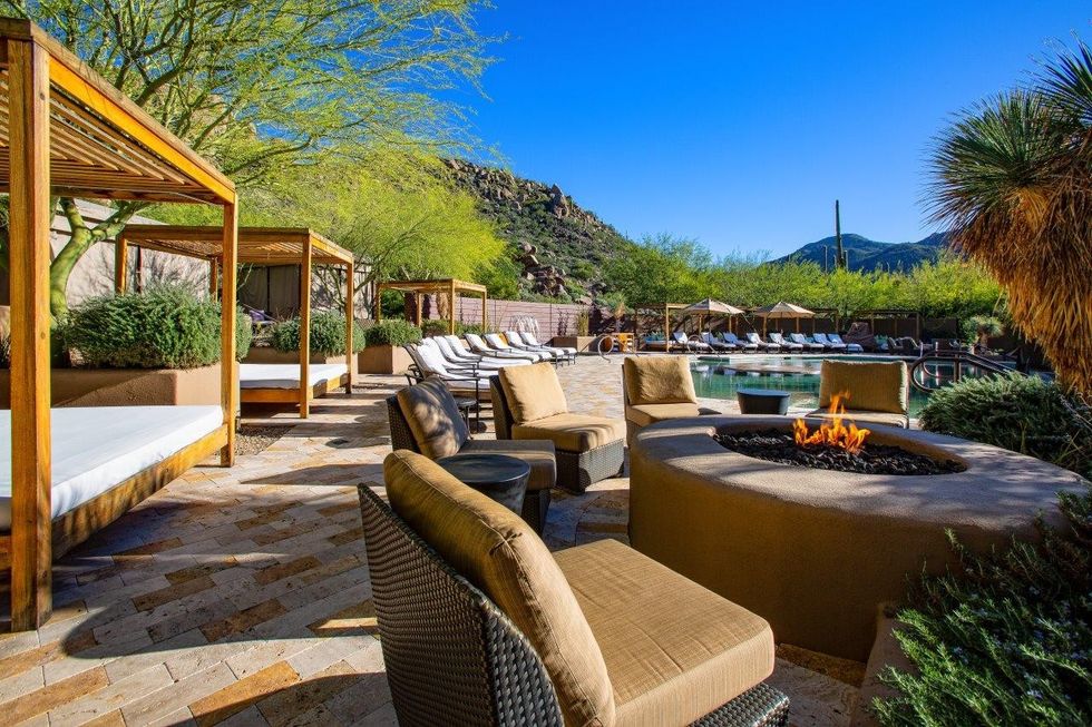 Luxury outdoor pool area with cabanas, fire pit, and mountain view.
