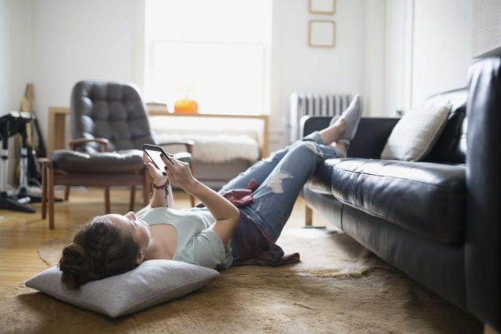 Lying on the floor, a woman uses a smartphone