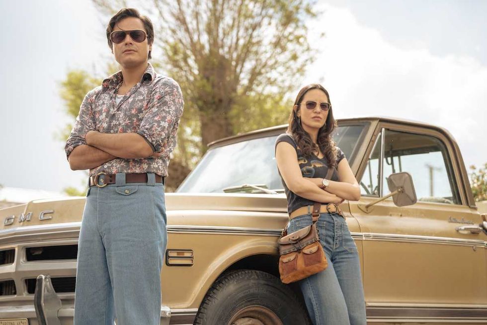 Man and woman in sunglasses pose confidently by vintage GMC truck.