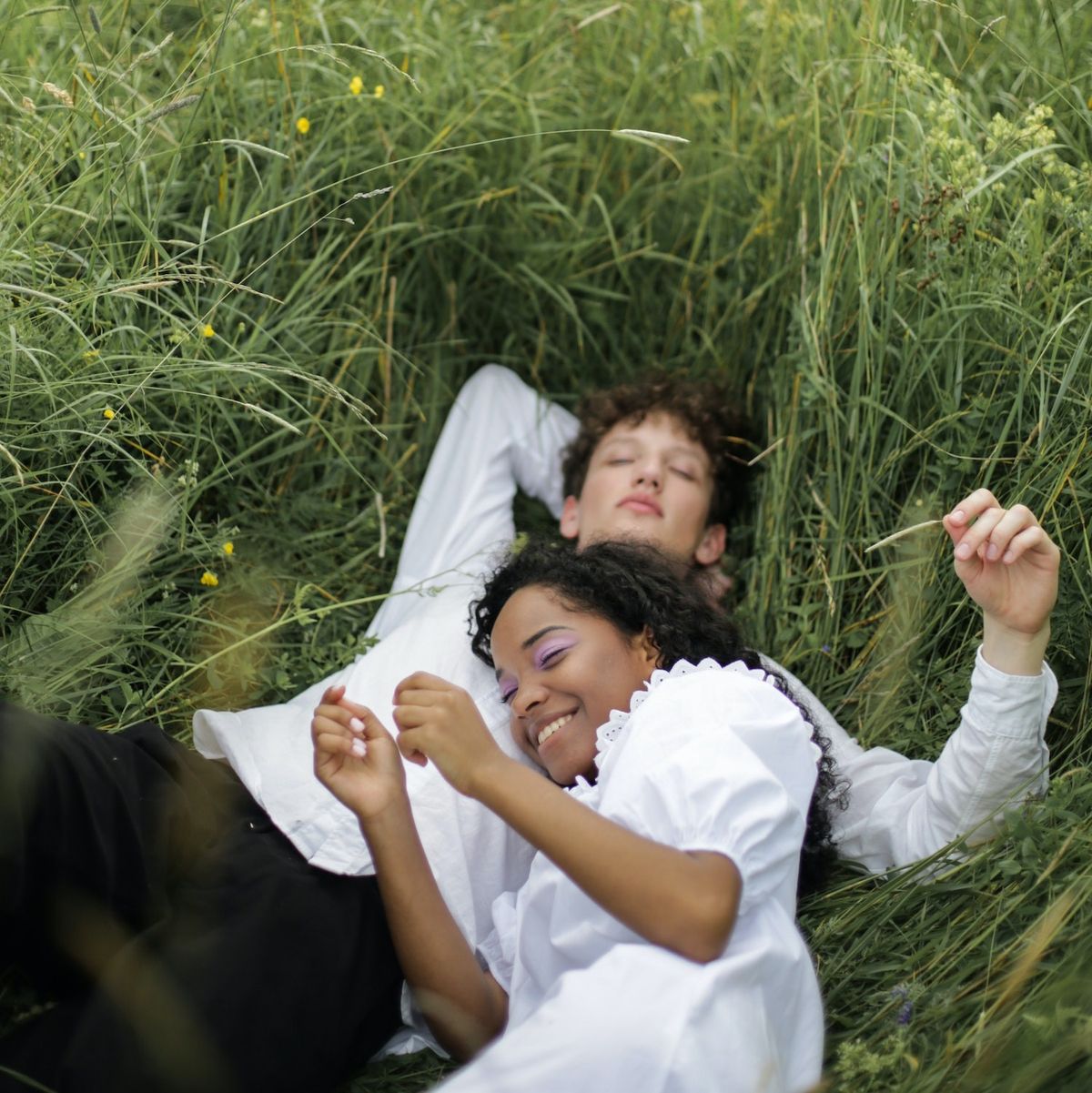 man and woman lying in the grass in the spring meet cute