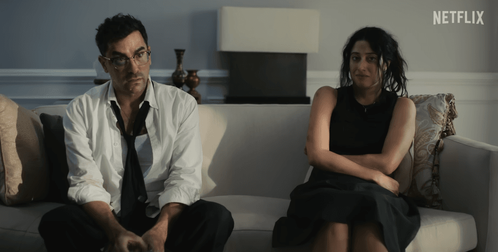 Man and woman sitting on a couch, looking tense, with Netflix logo in the corner.