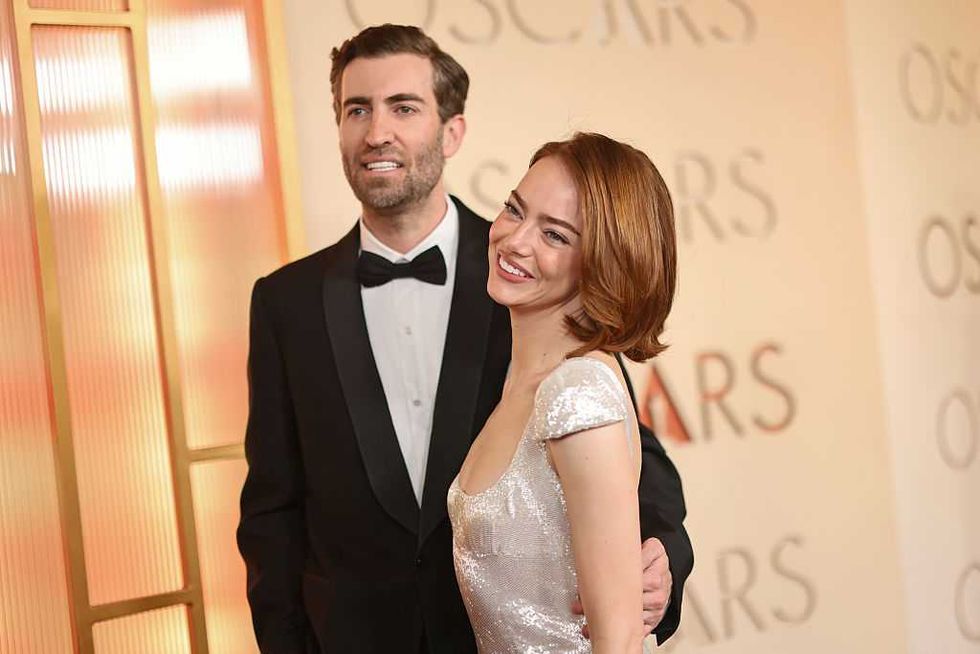 Man and woman smiling on the Oscars red carpet.