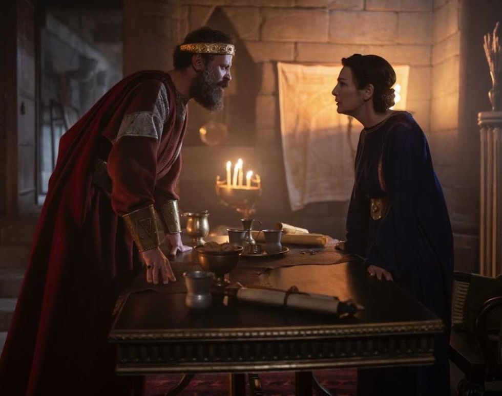 man and woman standing over a desk talking