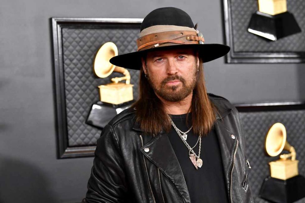 Man in black leather jacket and hat at a Grammy Awards event.