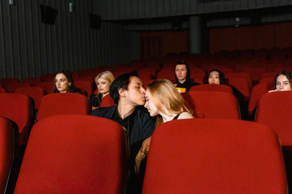 man kissing woman's forehead in move theater date ideas