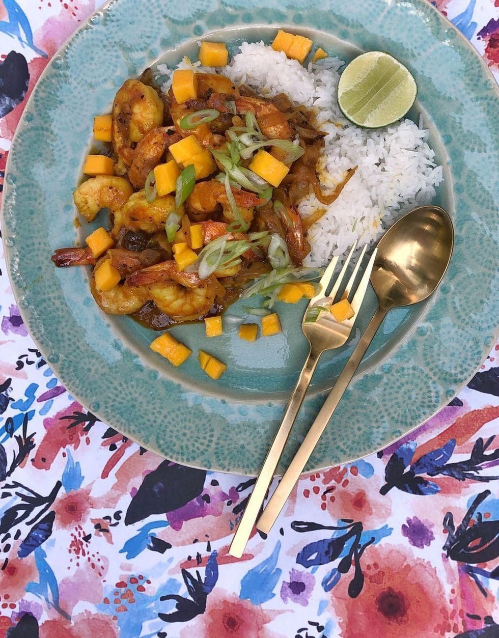 mango curry shrimp meal with rice and lime on a colorful floral tablecloth