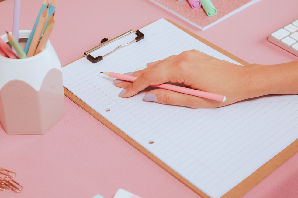 mercury retrograde girl holding pink pencil taking notes on white paper