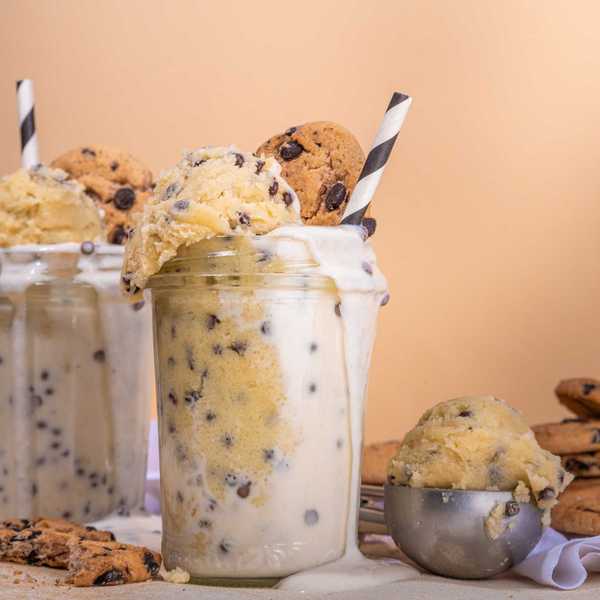 Milkshake with cookie dough and cookies in a glass jar with striped straw.