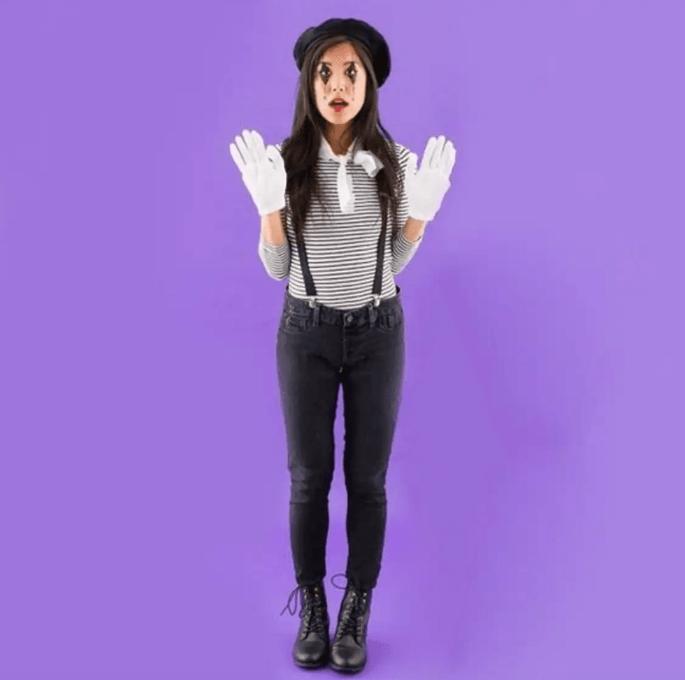 Mime in striped shirt and beret on a purple background with white gloves raised.