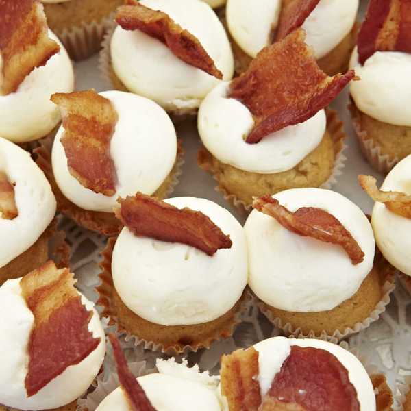 Mini cupcakes with white frosting, topped with crispy bacon.