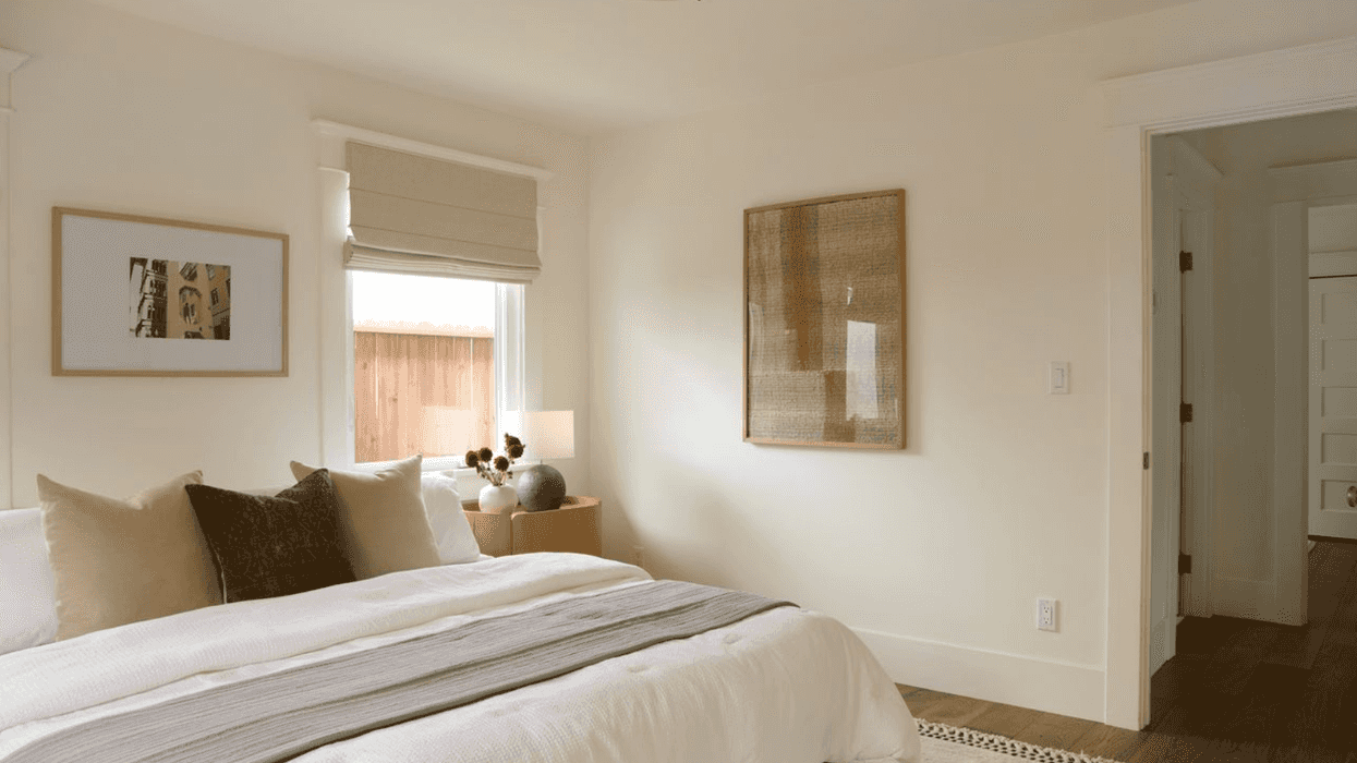 Minimalist bedroom with white bedding, neutral decor, and soft lighting.