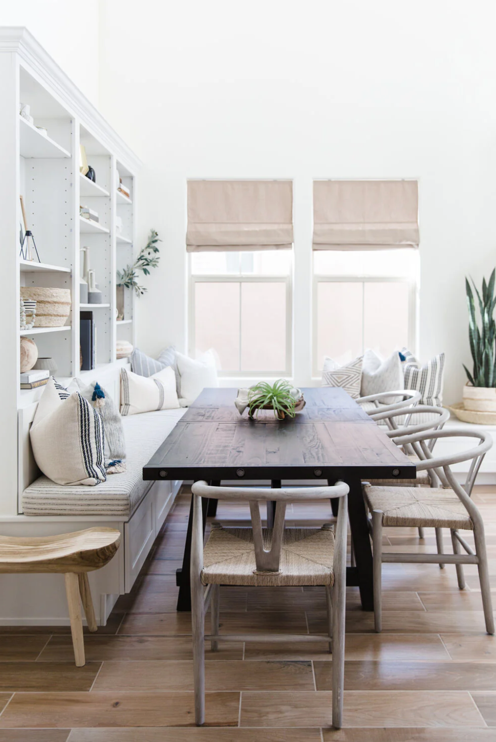Minimalist dining area with wooden table, chairs, built-in shelves, and soft natural lighting.