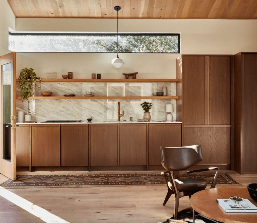 Minimalist kitchen with wooden cabinetry, large window, and hanging shelf decor.