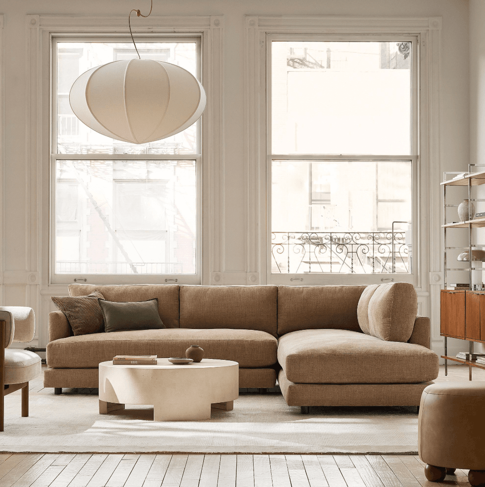 Minimalist living room with a beige sectional, round table, and large windows.