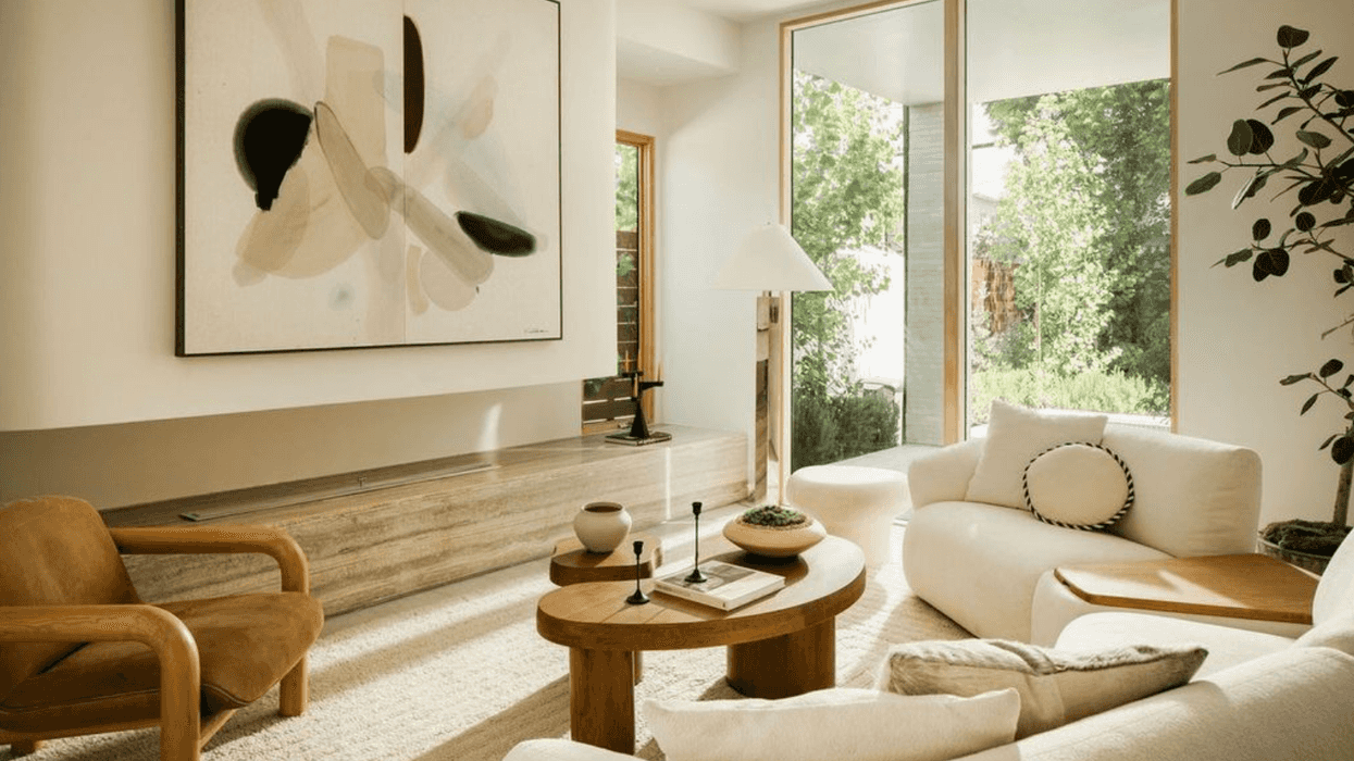 Minimalist living room with abstract art and large windows with garden view.