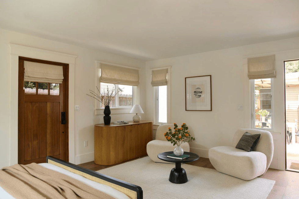 Minimalist living room with neutral tones, plush chairs, and a wooden console.