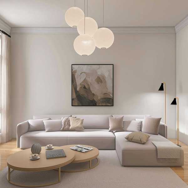 Minimalist living room with sofa, abstract art, round tables, and pendant lights.