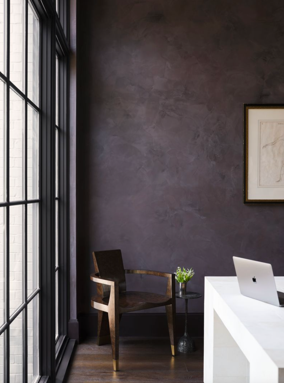Minimalist room with chair, table, laptop, and large windows. Dark textured wall.