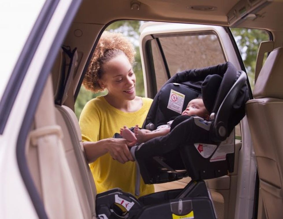 Mixed race mother loading baby into car seat