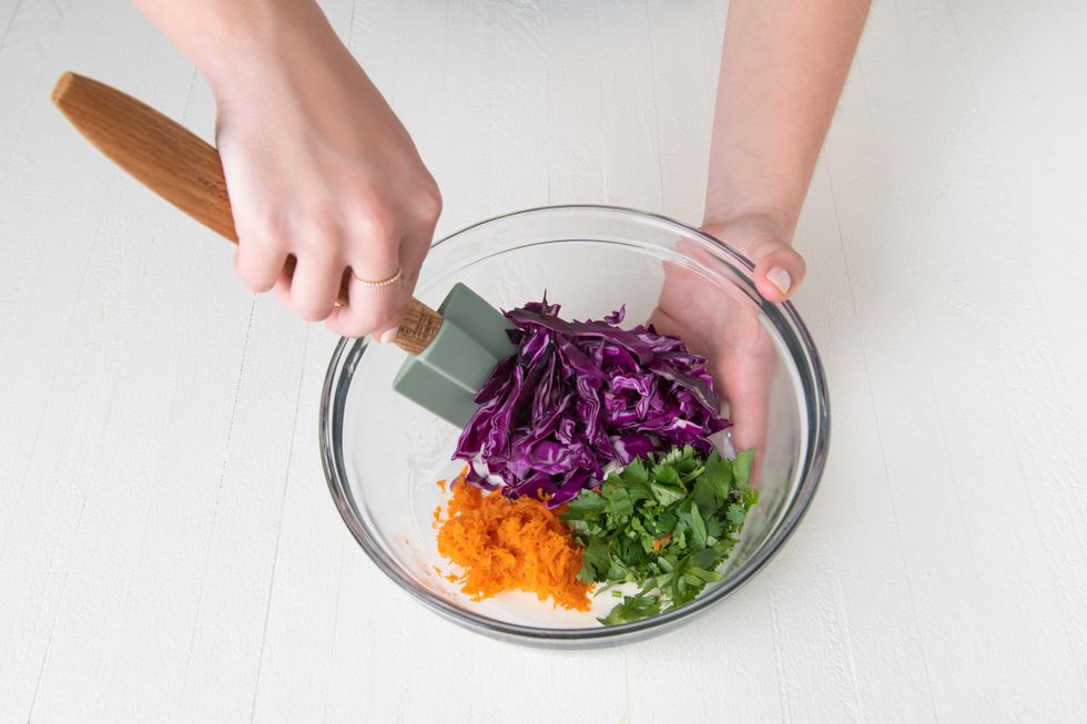 mixing taco slaw together with carrots cabbage and cilantro