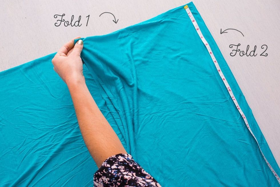 model folds fabric to make a blue Beach_Cover_Up