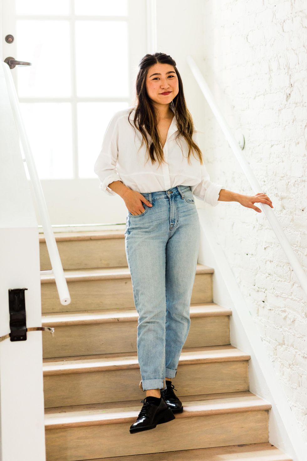 model on the stairs in a white blouse and jeans