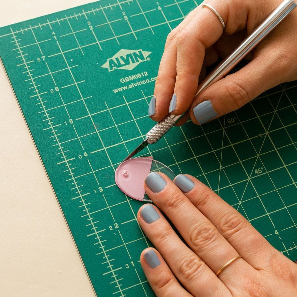 model traces the shape of the earring onto the vinyl and cuts it out with the x acto knife