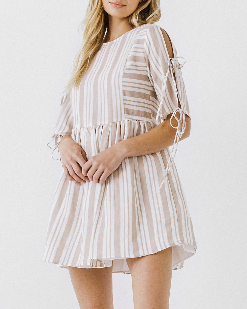 model wears tan and white striped mini dress with tie sleeves