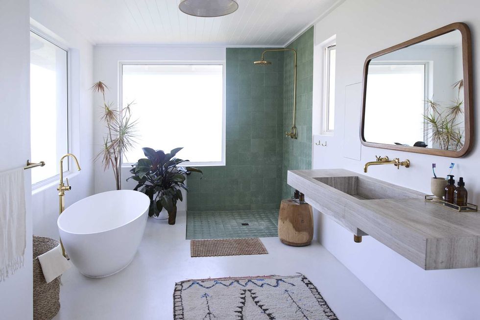 Modern bathroom with green shower, freestanding tub, and a large mirror above a stone sink.