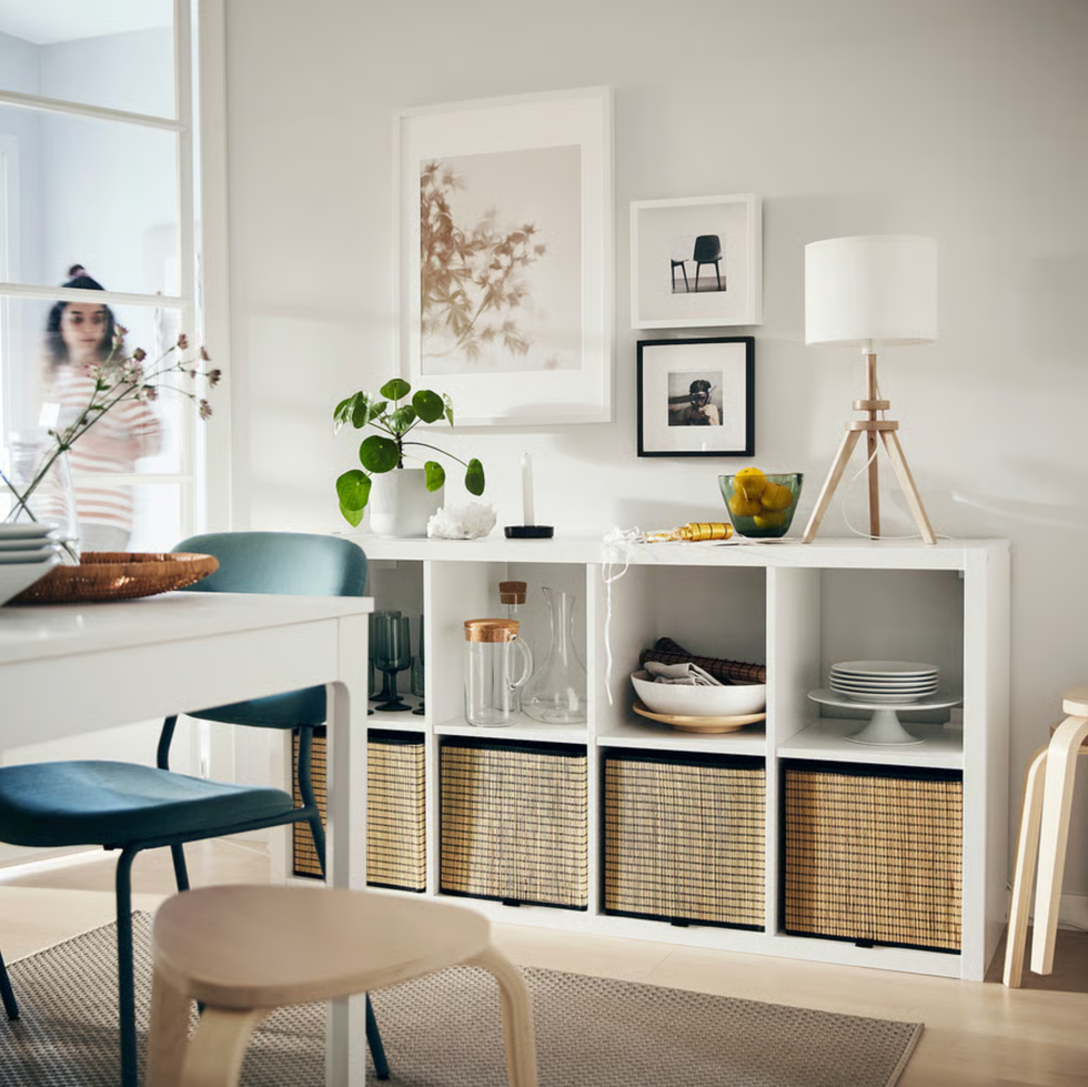 Modern dining room with shelves, framed art, and a woman near the door.