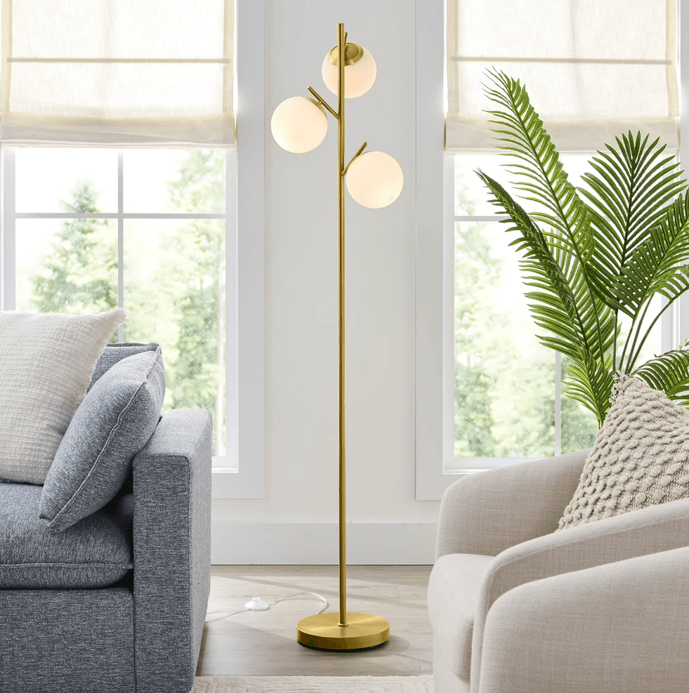 Modern gold floor lamp with three globe lights in a bright living room.