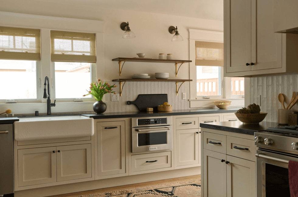 Modern kitchen with beige cabinets, black countertops, and open shelves.