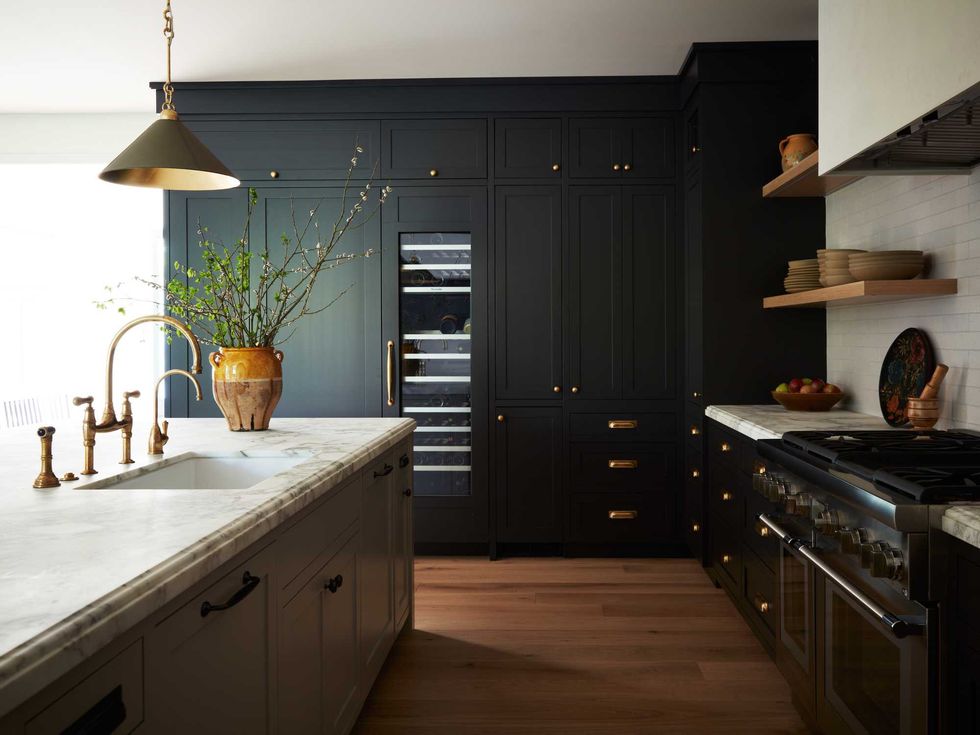 Modern kitchen with dark cabinets, marble countertops, and elegant brass fixtures.