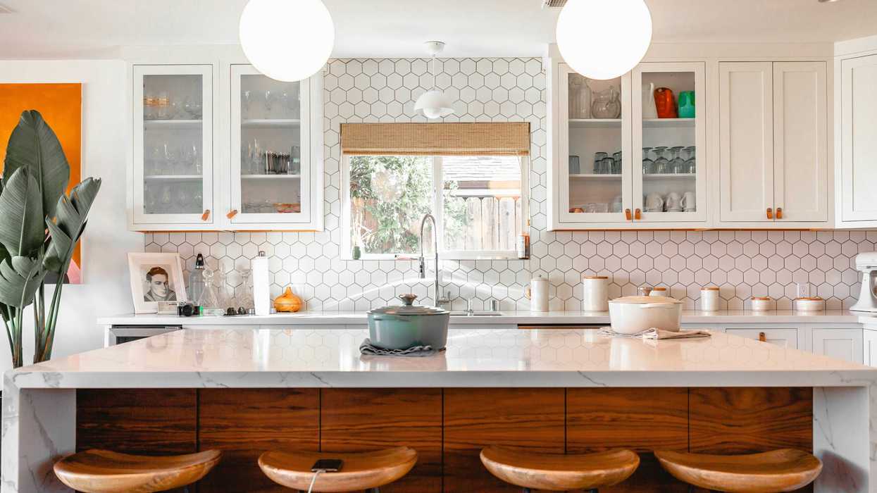 Modern kitchen with hexagonal tiles, wooden stools, and pendant lights over an island.