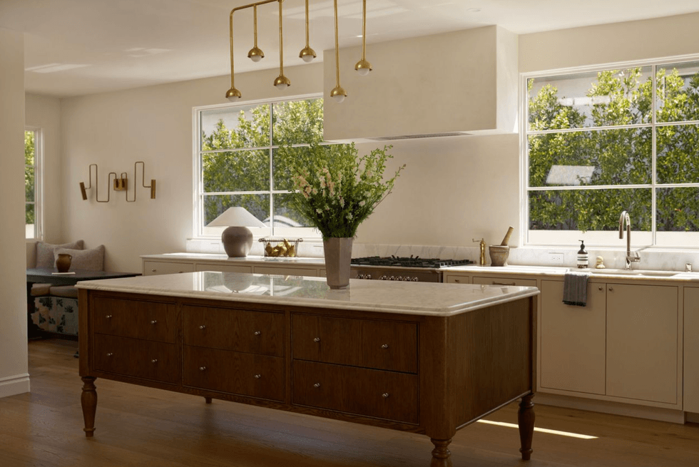 Modern kitchen with large island, pendant lights, and greenery in the window.