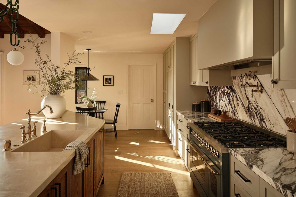 Modern kitchen with marble countertop, large stove, skylight, and dining area.
