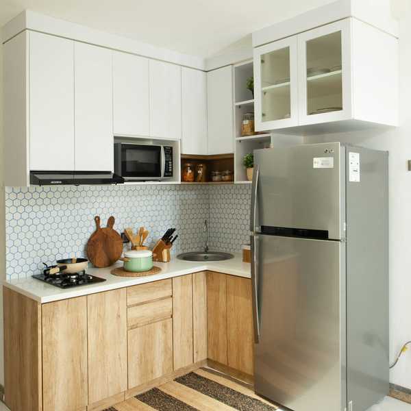 Modern kitchen with wood cabinets, stainless fridge, hex tile backsplash, and striped rug.