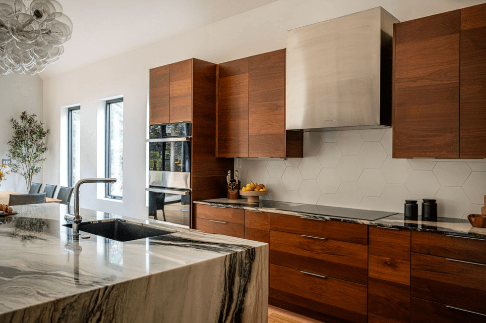 Modern kitchen with wooden cabinets, marble island, and hexagonal tile backsplash.
